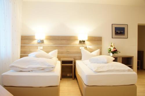 two beds in a hotel room with white pillows at Hotel Spitzenpfeil in Michelau