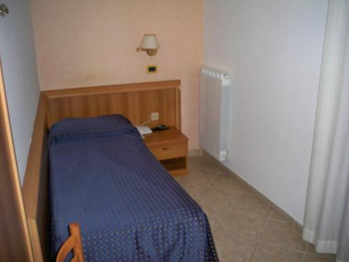 a small bedroom with a blue bed and a table at Albergo Corradetti in Castel di Sangro