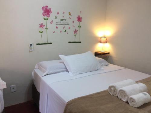 a bedroom with a white bed with flowers on the wall at Pousada Flor de Debora in Alto Paraíso de Goiás