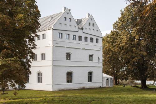a white house on a field with trees at Gutshaus Üselitz in Poseritz