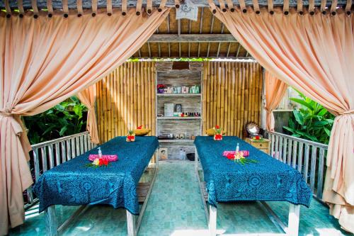 two blue tables in a room with curtains at The Syron Huts Lembongan in Nusa Lembongan