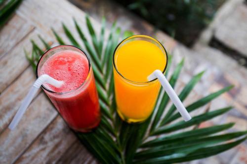 two cocktails sitting on a wooden table with palm leaves at The Syron Huts Lembongan in Nusa Lembongan