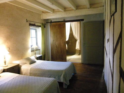 1 dormitorio con 2 camas y puerta que da a un pasillo en Les Gîtes de l'Astrée, en Saint-Bris-des-Bois