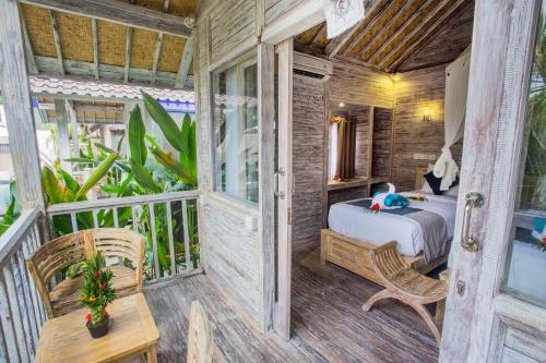 a bedroom with a bed and a table on a balcony at The Syron Huts Lembongan in Nusa Lembongan