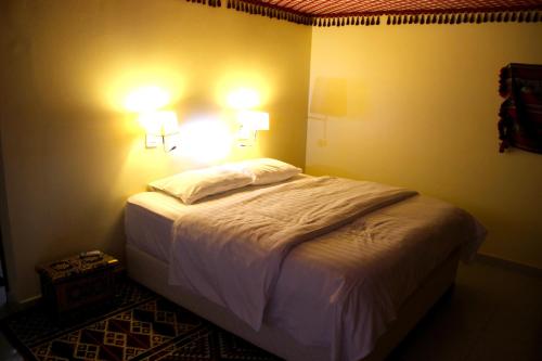 a bedroom with a bed with two lights on the wall at Arabian Oryx Camp in Shāhiq