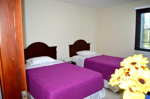two beds in a room with purple sheets at Sol Caribe Hotel in Soledad