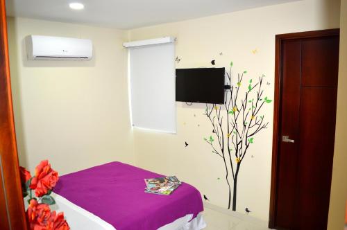 a room with a bed and a tv on the wall at Sol Caribe Hotel in Soledad