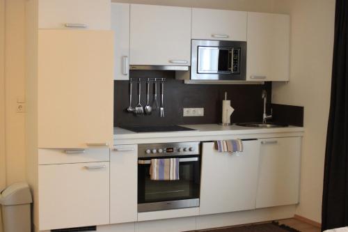 a white kitchen with a stove and a microwave at Gästehaus Waldrand Garni in Wiesing