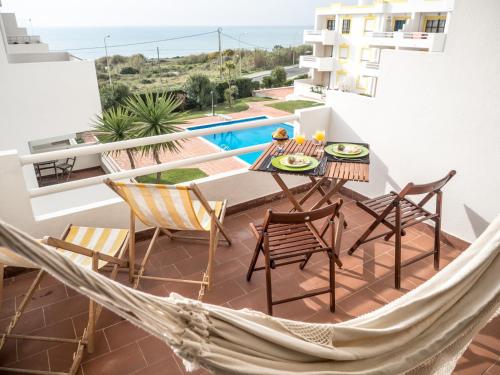 a hammock on a balcony with a table and chairs at Ericeira Sea View - Mar à Vista in Ericeira