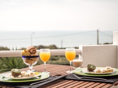 a table with two plates of food and two glasses of orange juice at Ericeira Sea View - Mar à Vista in Ericeira