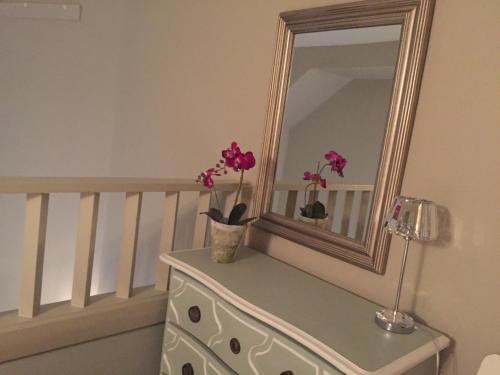a mirror on top of a dresser with flowers on it at Drummond Apartment in Edinburgh