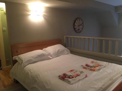 Una cama con dos toallas y un reloj en la pared. en Drummond Apartment, en Edimburgo