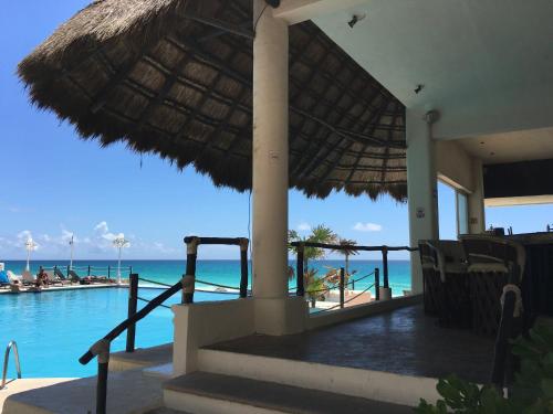 a resort with a pool and an umbrella and the ocean at Cancun Plaza - Best Beach in Cancún