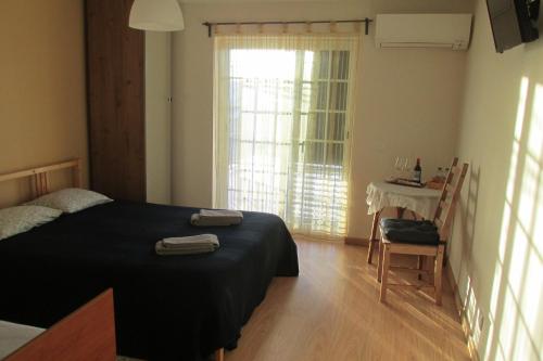 a bedroom with a bed and a table and a window at Residencial Marialva Park in Corroios