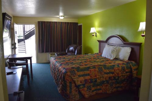 Habitación de hotel con cama y silla en Claremore Motor Inn en Claremore