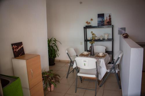 a dining room with a table and white chairs at Las Palmas in Zihuatanejo
