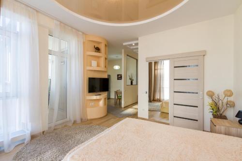 a white bedroom with a large bed and a television at Panorama Apartment in Dnipro