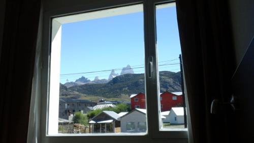 a window with a view of a town and mountains at Kau Si Aike in El Chalten