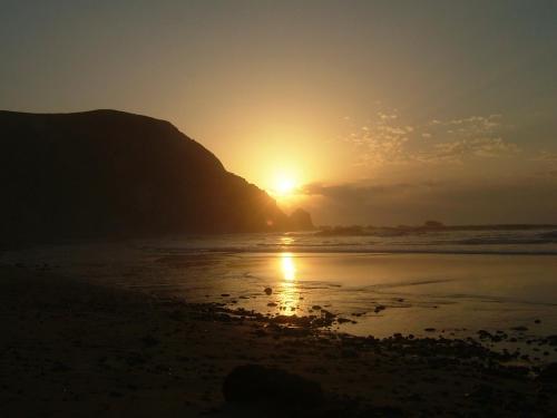 a sunset on the beach with a mountain in the background at Cantinho da Avó in Vila do Bispo