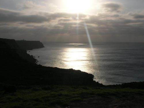 a sun setting over the ocean on a cliff at Casa Luana - Rooms in Sagres