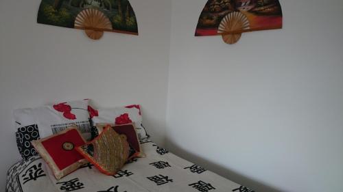 a bed with oriental pillows and paintings on the wall at Studio mobiliado in Santos