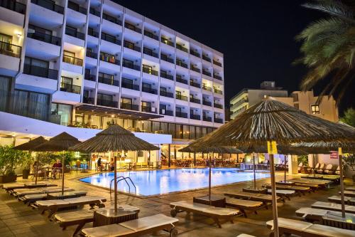 a pool with tables and umbrellas next to a hotel at Blue Sky City Beach Hotel in Rhodes Town