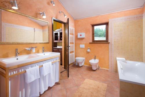 a bathroom with two sinks and a toilet and a mirror at Villa Valmont in Labin