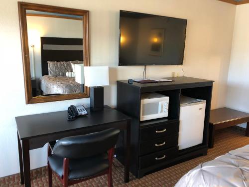 um quarto de hotel com uma secretária com um micro-ondas e um espelho em Big Chief Motel em Battle Mountain