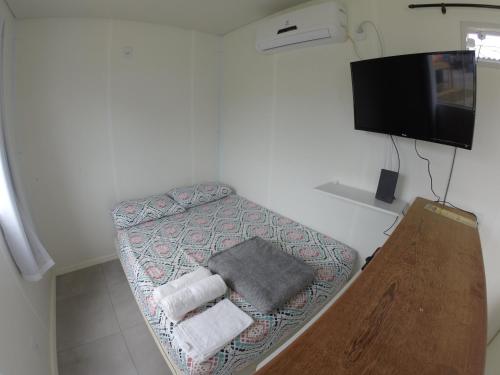 Habitación pequeña con 1 cama con toallas y TV de pantalla plana. en Pousada Beach Box, en Florianópolis