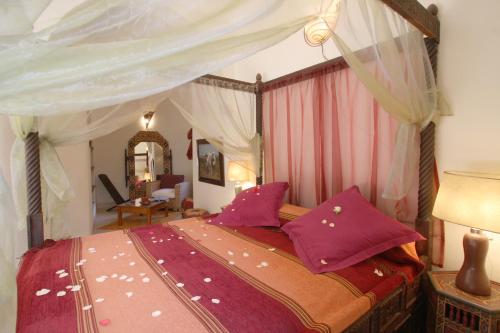 a bedroom with a canopy bed with purple pillows at Riad Cannelle in Marrakesh