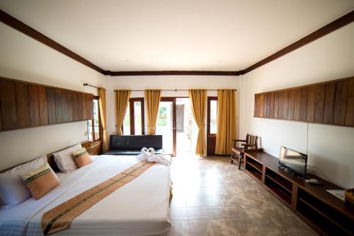 Rungnara pool villa في شيانغ ماي: غرفة نوم بسرير كبير وتلفزيون