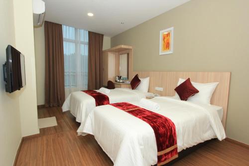 a hotel room with two beds and a television at Veer Hotel in Kuantan