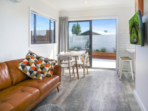 a living room with a brown leather couch and a table at Twizel Cottages in Twizel