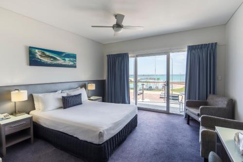 a bedroom with a bed and a balcony with the ocean at Ocean Centre Hotel in Geraldton