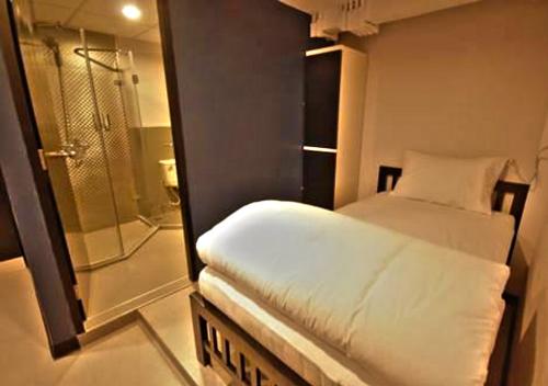 a small room with a bed and a shower at The Blocks Hostel Sukhumvit 10 in Bangkok