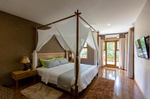 une chambre avec un grand lit à baldaquin dans l'établissement West Sands, à Ukulhas