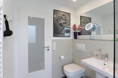 a white bathroom with a toilet and a sink at Ferienwohnung Welcome mit Seeblick in Schalkenmehren