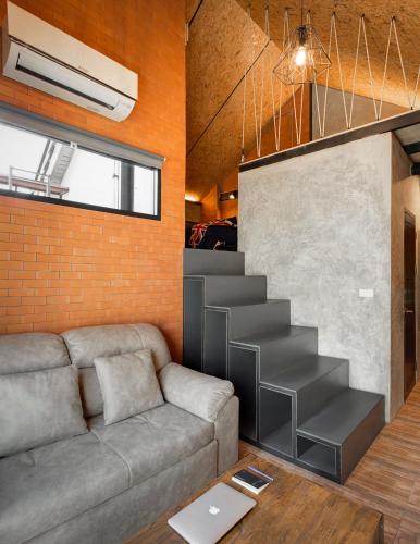 a living room with a couch and a staircase at The Step Chiang Mai in Chiang Mai