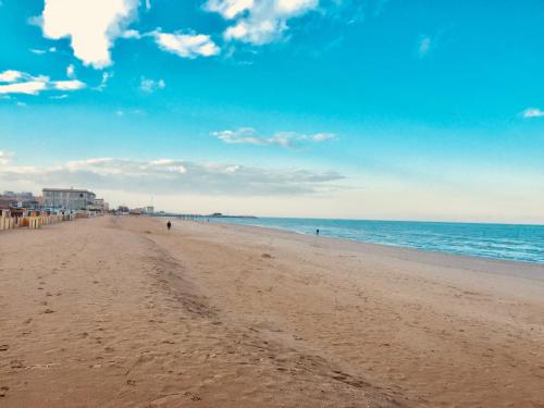 a beach with people walking on the sand and the ocean at Hotel Athena in Pesaro