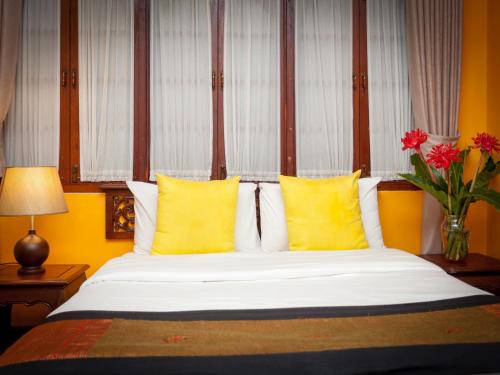a bedroom with a large bed with yellow pillows at Chandara Boutique Hotel in Vientiane