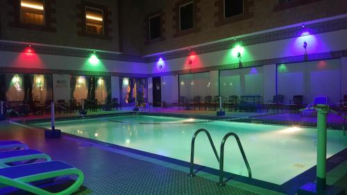 a swimming pool with chairs and lights in a building at Ramee Guestline Hotel in Muscat