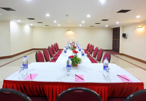 a long table in a room with red chairs and water bottles at Trichur Towers in Trichūr