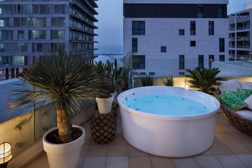 a large bath tub on a balcony with palm trees at Brown Beach House Tel-Aviv, a member of Brown Hotels in Tel Aviv