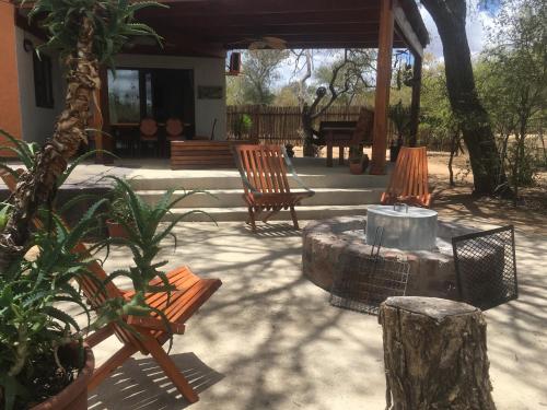 a patio with two chairs and a table and a tree stump at Mushi Maningi in Hoedspruit
