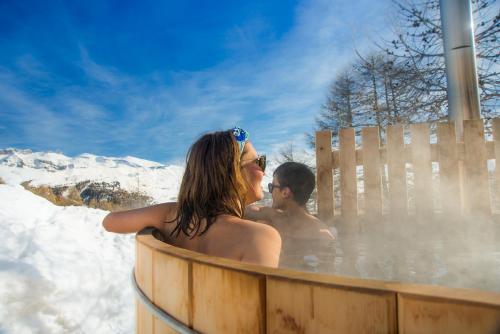a man and woman in a hot tub in the snow at le Chal'heureux in Vars