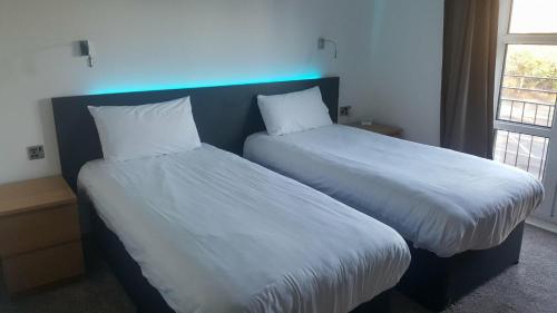 a bedroom with two beds with white sheets at The Gilvenbank Hotel in Glenrothes