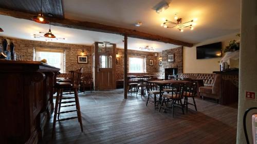 a bar with wooden tables and chairs in a restaurant at The Horseshoe Inn in Crickhowell