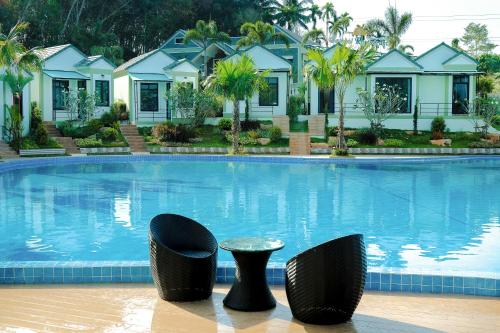 a large swimming pool with two chairs and a table at Saichon Grand View in Ban Lam Rua Taek