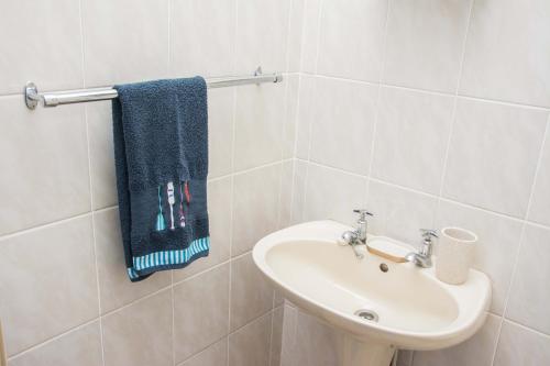 a white bathroom with a sink and a blue towel at Sea View Holiday Flat - 16 La Luce Margate in Margate