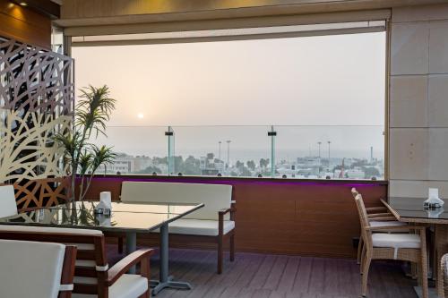 a restaurant with a large window and tables and chairs at Konoz Al Yam Hotel Jeddah in Jeddah